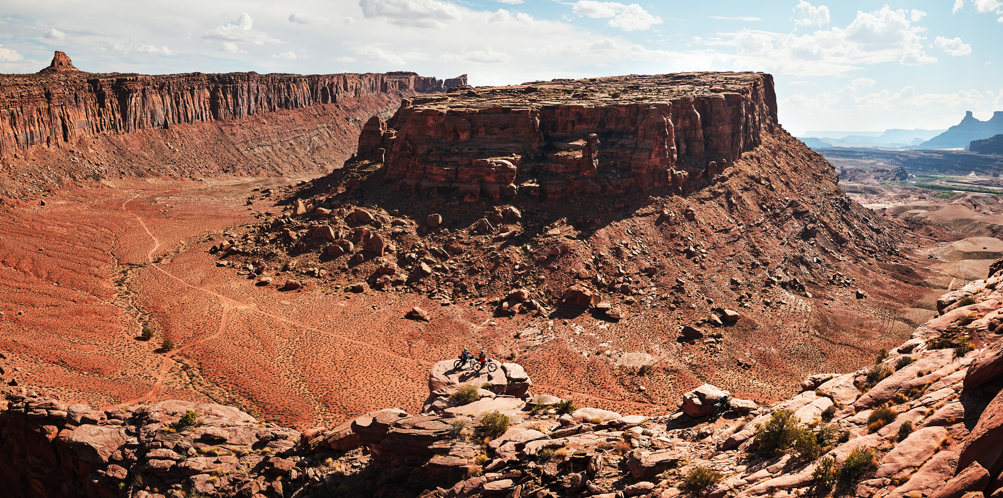 Two cyclists standing with their bikes on a ledge overlooking Canyonlands during a self-supported bikepacking trip.